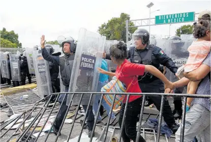  ?? Photo / AP ?? Federal police in riot gear herd a Honduran migrant family through the Mexican border.