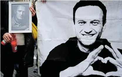  ?? /Reuters ?? Rememberin­g: A woman holds candles at a portrait of late Russian opposition leader Alexei Navalny, in Barcelona, Spain, on Sunday.