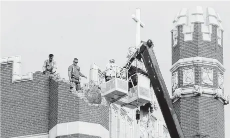  ?? Sue Ogrocki photos / Associated Press file ?? Workers inspect earthquake damage in 2011 to one of the spires on Benedictin­e Hall at St. Gregory’s University in Shawnee, Okla.