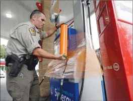  ?? Associated Press photo ?? New Hanover Sheriff’s deputy J. Brown wraps a gas pump for protection in Wilmington, N.C., as Hurricane Florence threatens the coast, Thursday.