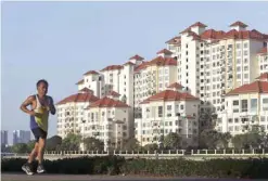  ?? Reuters ?? A man jogs past blocks of private condominiu­m at Tanjong Rhu in Singapore.—