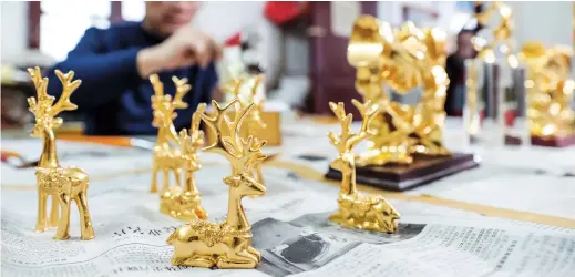  ??  ?? Craftwork decorated by gold foil is displayed at Nanjing Goldthread & Goldfoil General Factory in the capital city of Jiangsu Province. — All photos by Xinhua