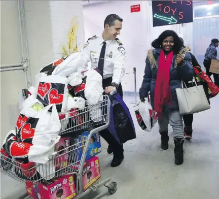  ?? MARIE-FRANCE COALLIER ?? Montreal police Insp. Pascal Jean pushes a grocery cart filled with food, diapers, and toys for Jerline Jean at Sun Youth on Tuesday. Sun Youth, a community service charity, has seen demand for its food bank jump by 35 per cent since the 2008 financial...