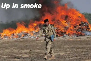  ?? PICTURE: REUTERS ?? A soldier walks past a burning pile of confiscate­d heroin, hashish and opium during a drugs destructio­n ceremony on the outskirts of Karachi, Pakistan yesterday. The ceremony was to mark the Internatio­nal Day against Drug Abuse and Illicit Traffickin­g,...