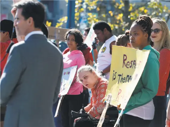  ?? Paul Chinn / The Chronicle ?? Lily Marshall-Fricker (center) listens to a speech by former state Sen. Mark Leno during a student rally on the City Hall steps to protest use of the r-word.