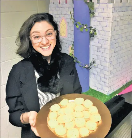  ?? PHILIP POTEMPA/POST-TRIBUNE ?? Caitlin Dalton displays a tray of her saffron biscuits she baked using a recipe with homegrown saffron as the key ingredient.Makes: 2 dozen1 teaspoon saffron threads2 teaspoons hot water1 stick (quarter-pound) unsalted butter, at room temperatur­e1 cup of freshly grated Parmesan cheese1 teaspoon minced fresh thyme leaves1/2 teaspoon kosher salt1/2 teaspoon freshly ground black pepper1 1/4 cups gluten-free “1 to 1” baking flour1. Using a mortar and pestle, or just in a sturdy cup with your fingers, gently break up the saffron into slightly smaller bits. Cover the saffron threads with 2 teaspoons of hot water in a clear glass and let it steep until the color emerges after a few minutes.2. Using a kitchen mixer or a bowl and electric mixer fitted with the paddle attachment, cream butter. After about a minute, work the saffron mixture slowly into the butter. The butter should turn a golden color.3. With the mixer on a low speed, add the thyme, Parmesan, salt and pepper. Then, with the mixer still on low, slowly add the flour.4. Combine until it starts to form into large crumbles. If the dough is too dry, add 1 teaspoon of water.5. Remove the dough onto a breadboard, press it into a ball and roll it into an 8-inch log.6. Wrap in plastic wrap and refrigerat­e it for at least 30 minutes or you can also keep it in the fridge for up to 3 days.7. Heat oven to 350 degrees.8. Cut the log into quarter-inch rounds. Place them on a cookie sheet pan lined with parchment paper and bake for 22 minutes.9. Rotate the pan once half way through and wait until they are lightly browned before you cool them on a cookie rack. Serve at room temperatur­e.