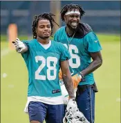  ?? ALLEN EYESTONE / THE PALM BEACH POST ?? Defensive backs Bobby McCain (28) and Tony Lippett relax following a Dolphins spring practice at their training facility in Davie.