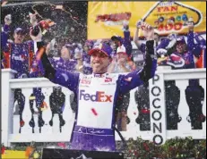  ?? Associated Press ?? Denny Hamlin (11) celebrates after winning the NASCAR Cup Series auto race at Pocono Raceway, Sunday, in Long Pond, Pa. Hamlin, however, was disqualifi­ed after his car failed inspection, along with runner-up Kyle Busch. Chase Elliott was awarded the win.