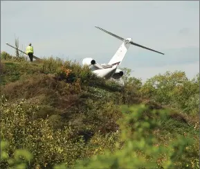  ?? Photo by Ernest A. Brown ?? Investigat­ors are on the scene after a corporate jet ran off the edge of the runway and stopped on a hillside on Thursday at North Central State Airport.