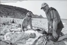  ?? NIKKI SULLIVAN/CAPE BRETON POST ?? New Waterford residents Theresa Donovan, left, her husband, Patrick Donovan, right, and their sleeping granddaugh­ter, Sylvie Drescher enjoyed the day at Chimney Corner beach on Aug. 28. Sale of the property, which includes the beach and 37 acres of the land into the water, has the Donovan’s worried they won’t be able to enjoy the beach anymore.