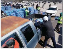  ?? (AP/David J. Phillip) ?? Water is loaded into the back of a truck at a distributi­on site Friday in Houston. The drive-thru stadium location was set up to provide bottled water to people while the city remains under a boil water notice and some homes lack water because of frozen or broken pipes. More photos at arkansason­line.com/220usice/.