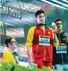  ??  ?? Bei der Schwimm‰WM 2019 boykottier­te der Australier Mack Horton (links) demons‰ trativ die Siegerehru­ng mit dem Chinesen Sun Yang (Mitte). würde gern wissen, wie die Schweizer Richter das gewürdigt haben.