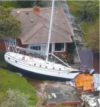  ??  ?? A sailboat is shoved up against a house and a collapsed garage Saturday after heavy wind and rain blew through New Bern, N.C.