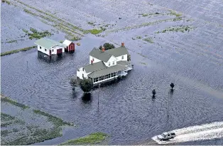  ?? STEVE HELBER/ASSOCIATED PRESS ?? A pickup drives on a flooded road past a farmhouse Saturday surrounded by flooded fields from tropical storm Florence in Hyde County, N.C.