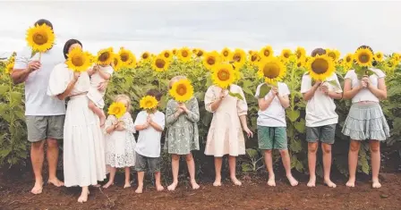  ?? ?? Rhys and Danielle Carroll and their eight children – including her sister Kelly Wilkinson’s three kids – pose with Kelly’s favourite flower on the one-year anniversar­y of her death this week. Picture: Jodie Dort Photograph­y