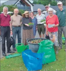  ??  ?? Members of Lamlash Improvemen­ts Associatio­n plant flowers in the village green tubs.