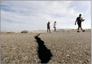  ?? AP/MARCIO JOSE SANCHEZ ?? People walk next to a crack in the road Sunday caused by an earthquake as they cross California 178 near Ridgecrest.