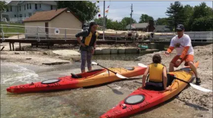  ?? RICHARD PAYERCHIN — THE MORNING JOURNAL ?? Robb Koscho of LoCo ‘Yaks extends a helping hand to Lexi Kim of Avon Lake as she prepares to exit a kayak at Avon Lake’s Veterans Park on June 7, as her mother, Jeana Kim, looks on. Local providers say paddlespor­ts are growing in Lorain County.