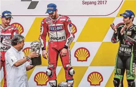  ?? PIC BY OSMAN ADNAN ?? Deputy Prime Minister Datuk Seri Ahmad Zahid Hamidi presents the trophy to MotoGP winner Andrea Dovizioso (centre) at the Sepang Circuit yesterday.