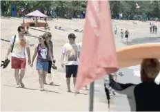  ?? — Reuters ?? Tourists stroll on Kuta Beach on the resort island of Bali on Tuesday.