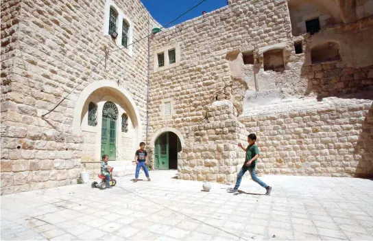  ??  ?? Palestinia­n children play with a ball outside their house in the old town of the divided West Bank city of Hebron in this file photo. (AFP)