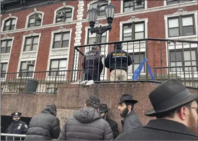  ?? (AP/Jake Offenhartz) ?? City inspectors and police officers wait outside the Brooklyn, N.Y., headquarte­rs of the Chabad movement on Tuesday. The building was evacuated after a tunnel was discovered Monday evening.