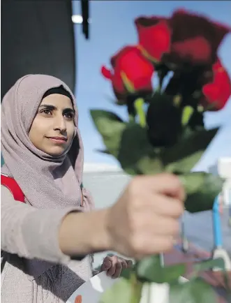 ?? LEAH HENNEL ?? Syrian newcomer, Nour Yassin, hands out roses to shoppers at Chinook Mall on Saturday to show her appreciati­on to Canadians.