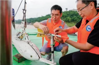  ??  ?? Hydrologic­al staff install a water flow meter on a fishing boat in Chongqing in southwest China on July 2