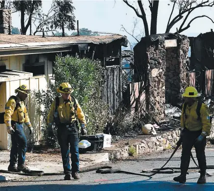  ??  ?? Des pompiers de Los Angeles arpentaien­t hier la route North Tigertail après le passage dévastateu­r du Getty Fire qui a démoli 12 maisons.