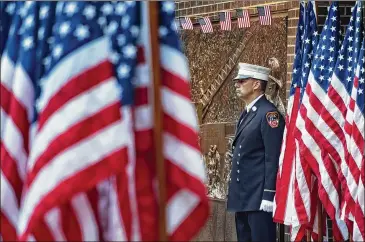  ?? CRAIG RUTTLE / ASSOCIATED PRESS ?? A New York City firefighte­r stands at attention by a memorial at the side of a firehouse adjacent to One World Trade Center and the 9/11 Memorial site during ceremonies on the anniversar­y of 9/11 on Tuesday.