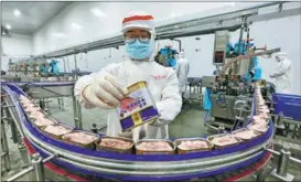  ?? ZHONG MIN / FOR CHINA DAILY ?? Workers process canned meat at a factory in Suining, Sichuan province.