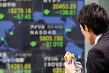  ?? PICTURE: AP ?? NO TIME FOR LUNCH: A man looks at the electronic stock board of a securities firm in Tokyo yesterday. Asian shares were mixed amid continuing worries about tensions on the Korean Peninsula.