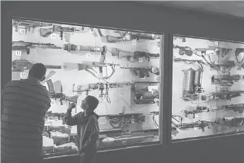  ??  ?? Snodgrass looks at a display case full of machine guns at the American Armoured Foundation Tank Museum.The museum also includes rifles, bazookas, flame throwers, historical helmets and headwear, 2,000 uniforms, flags, military patches, dioramas and more.