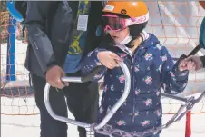  ?? ?? Orlando Torres helps his student get onto the caterpilla­r ride on (March 3).