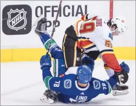  ?? The Canadian Press ?? Calgary Flames forward Dillon Dube ends up on top of Vancouver Canucks’ Kole Lind during second-period NHL preseason action in Vancouver on Wednesday night. The Canucks lost 4-1.