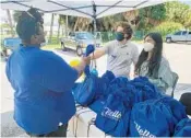  ?? THE LORDS PLACE ?? Spanish River High School students Nishah Jaferi and Jonathan Beres hand out one of their kits to an appreciati­ve recipient during a distributi­on at The Lord’s Place homeless shelter inWest PalmBeach.