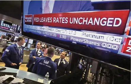  ??  ?? Status quo: The rate decision of the Federal Reserve appears on a television screen on the floor of the New York Stack Exchange on Wednesday. The Fed says it will start in October to gradually unwind its US$4.5 trillion balance sheet, which expanded to...