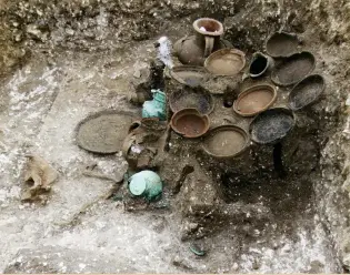  ??  ?? Right: Local and imported tablewares in situ on the remains of a table in a grave at the Pepper Hill Roman cemetery, Kent
Below: Impression by Sue Moodie of the Little Lane cellar, Roman Leicester, showing olive oil and wine amphorae on the floor and a “tazza” and flagons on shelf above