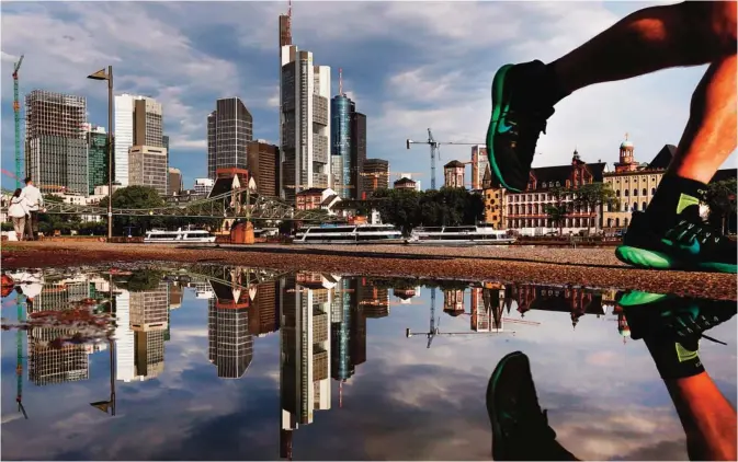  ?? —AP ?? FRANKFURT: The skyline of the banking district is reflected in a puddle after a heavy thundersto­rm during the night in Frankfurt yesterday.