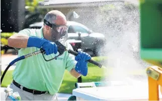  ?? MARIA LORENZINO/STAFF PHOTOGRAPH­ER ?? Spiro Edgos uses a power sprayer to clean the outside of the bins, then sprays down the grunge inside.