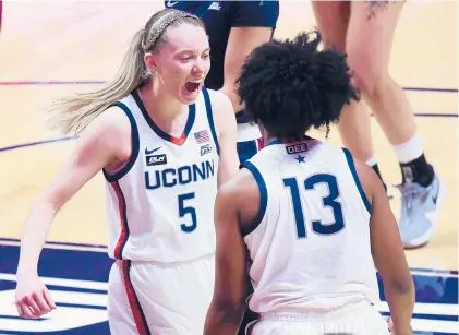  ?? BRAD HORRIGAN/HARTFORD COURANT ?? UConn guard Paige Bueckers, left, celebrates a basket with Christyn Williams during a quarterfin­al game against St. John’s in the Big East Tournament at Mohegan Sun Arena on Saturday in Uncasville. UConn won 77-41.