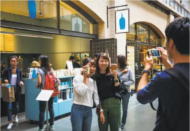  ?? Photos by Gabrielle Lurie / The Chronicle ?? One of Blue Bottle Coffee’s stands at the Ferry Building serves as a background for visitors’ photos. Below: Blue Bottle drinks often are a work of art for the eyes, as well as the palate.