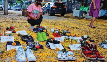  ?? | AFP ?? A WOMAN looks at shoes displayed with flowers in Yangon’s Myaynigone township, as part of the ‘Marching Shoes Strike’ called on social media to protest against the demonstrat­ion against the military coup in Myanmar, yesterday.