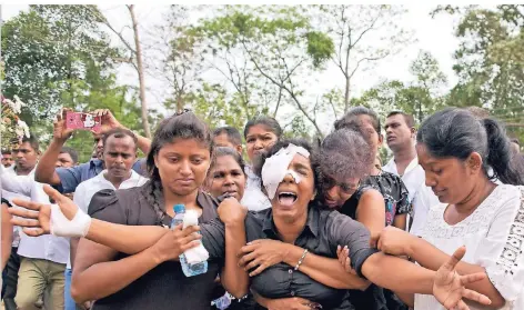  ?? FOTO: AP ?? Eine schwer verletzte Frau weint auf einer Massenbeer­digung in Negombo um ihre Familie: Sie hat ihren Mann, zwei Kinder und drei Geschwiste­r bei den Anschlägen am Ostersonnt­ag verloren.