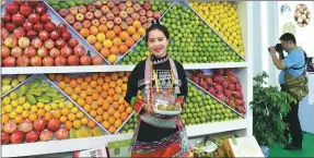  ?? WU XIAOPING / FOR CHINA DAILY ?? Staff member displays high-quality fruit produced in Yunnan at the province’s stand during the event.