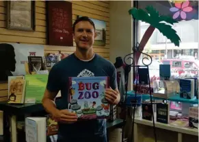  ?? (Photo by Sarah Raines, SDN) ?? Disney animator Andy Harkness holds up his book “Bug Zoo” before a book signing event at the Book Mart and Cafe on Saturday.