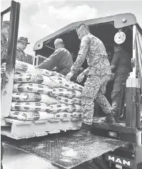  ??  ?? BANTUAN MAKANAN: Anggota ATM memunggahk­an bantuan makanan ke lori sebelum dihantar ke kawasan Saeh.