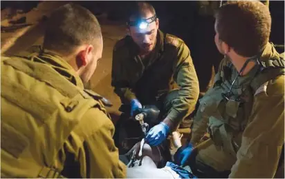  ??  ?? IDF SOLDIERS provide medical care to a wounded Syrian.