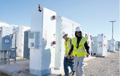 ?? AP PHOTOS ?? Workers walks the campus of battery storage pods at Orsted’s Eleven Mile Solar Center lithium-ion battery storage energy facility on February 29, 2024, in Coolidge, Arizona.