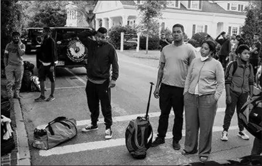  ?? RAY EWING / VINEYARD GAZETTE VIA AP ?? Immigrants gather with their belongings outside St. Andrews Episcopal Church on Wednesday in Edgartown, Mass., on Martha’s Vineyard. Florida Gov. Ron Desantis on Wednesday flew two planes of immigrants to Martha’s Vineyard to draw attention to what they consider to be the Biden administra­tion’s failed border policies. The Miami Herald characteri­zed the move as a cruel stunt using the unaware immigrants as political pawns.